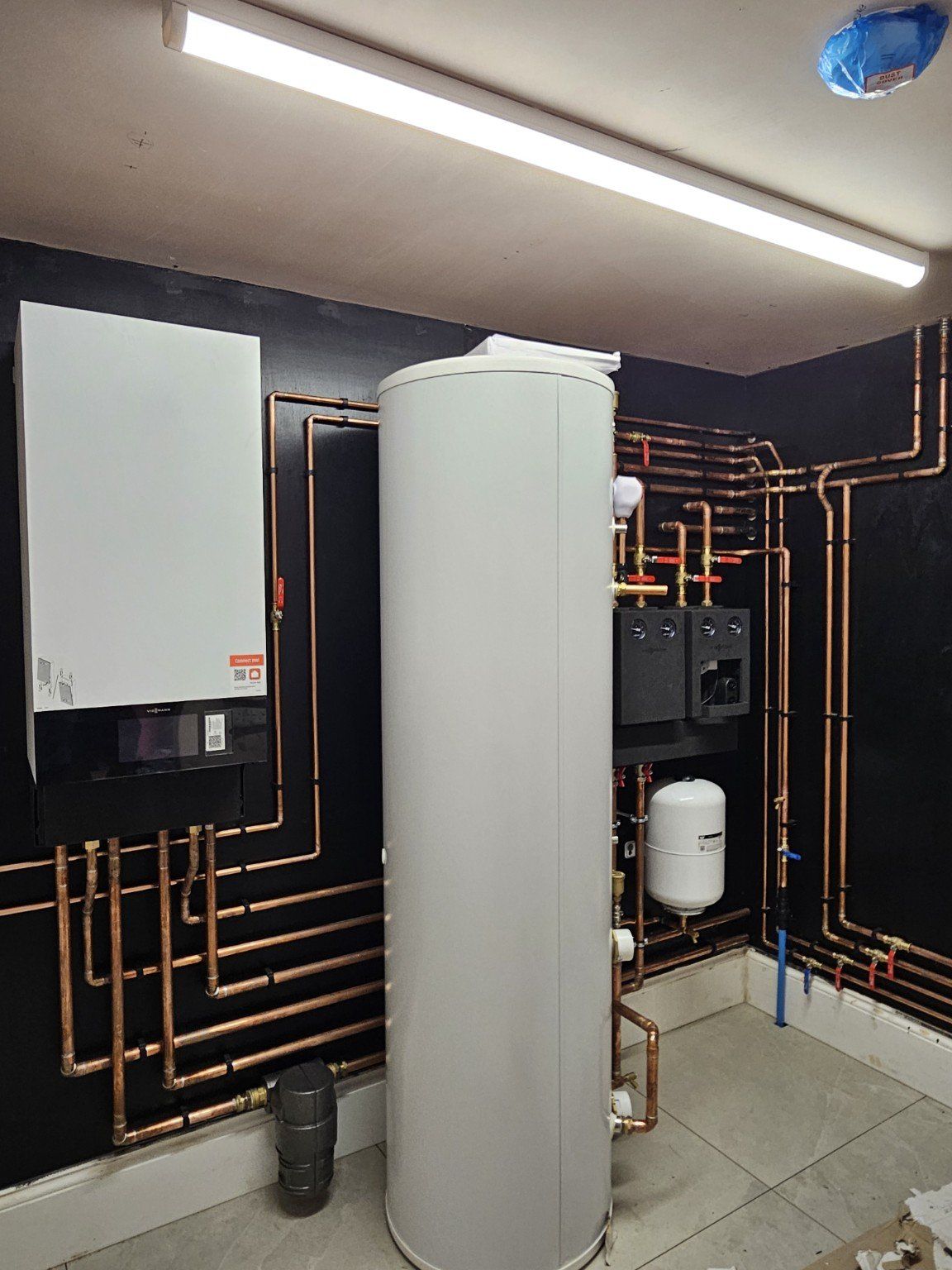 Completed plant room installation with neat copper pipework, hot water cylinder and heating components